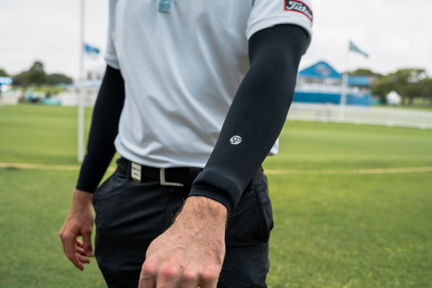 Person wearing black sleeves on a sports field with visible branding.
