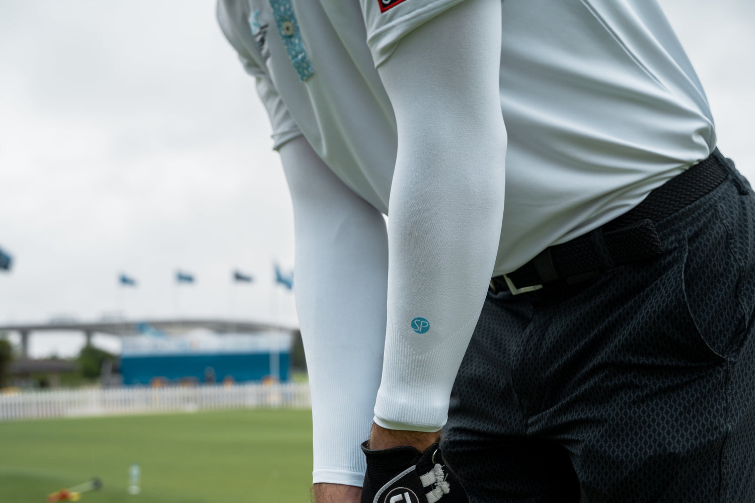 Person holding a golf club on a golf course with blurred background